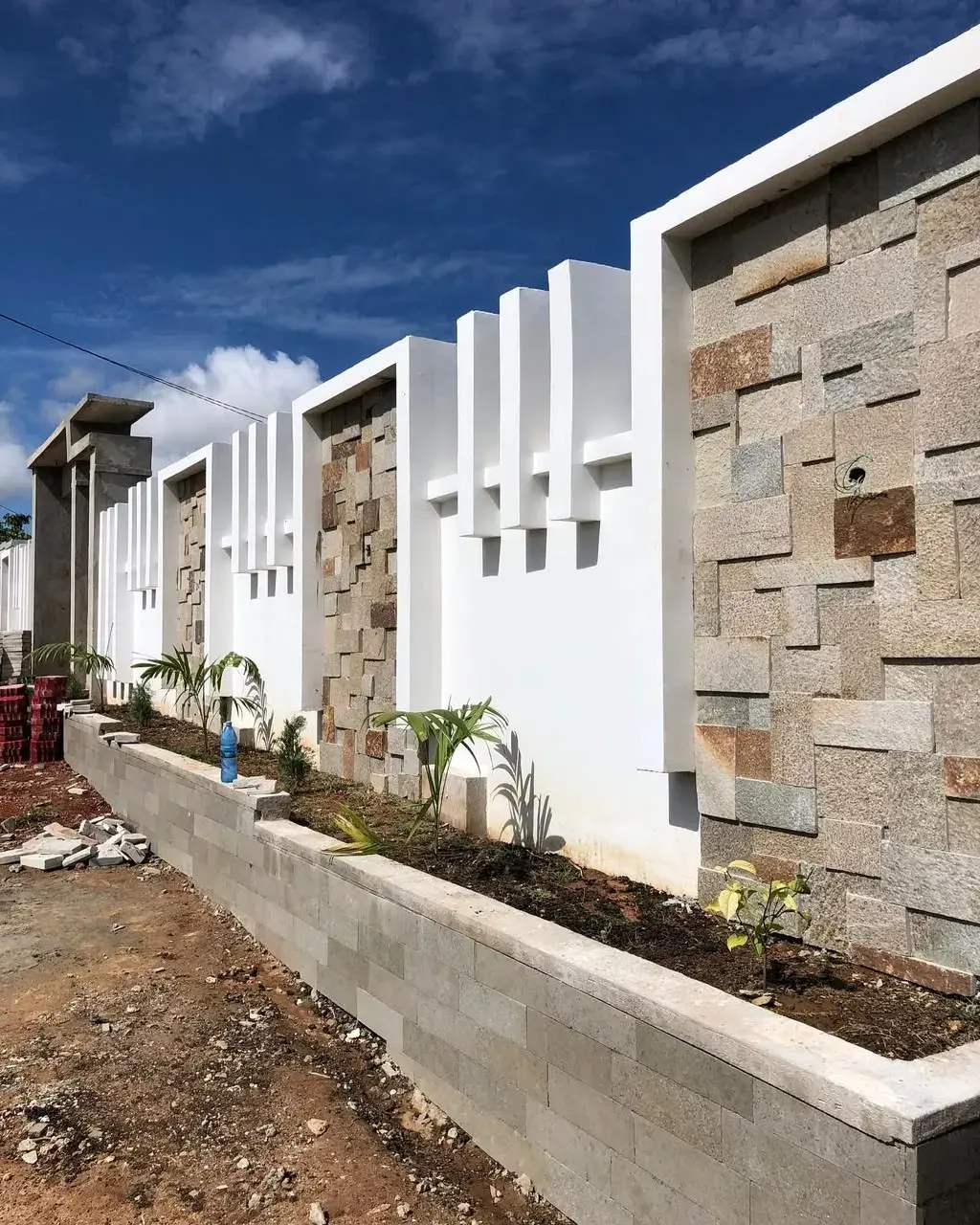Boundary wall clad in Babati stone, with a planter