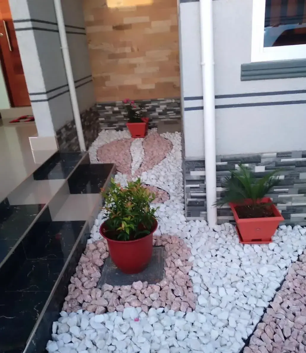 Entrance garden with pink and white stones and potted plants