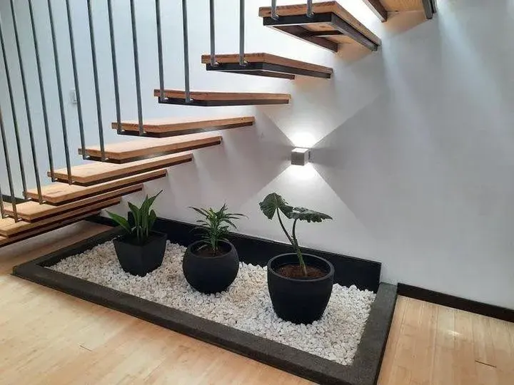 White stone bed with potted plants under wooden stairs
