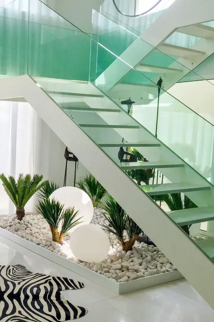 White pebble garden with palms under a glass staircase